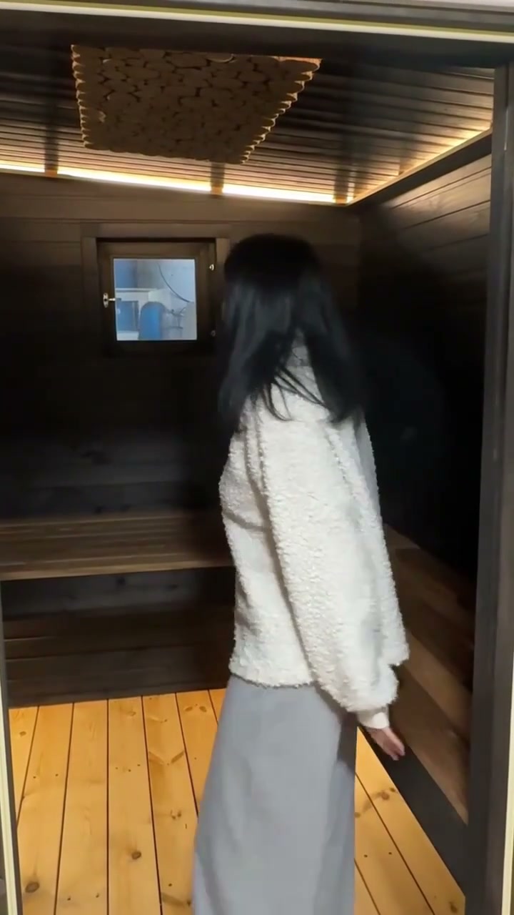 A sauna with a black steam room and a juniper panel